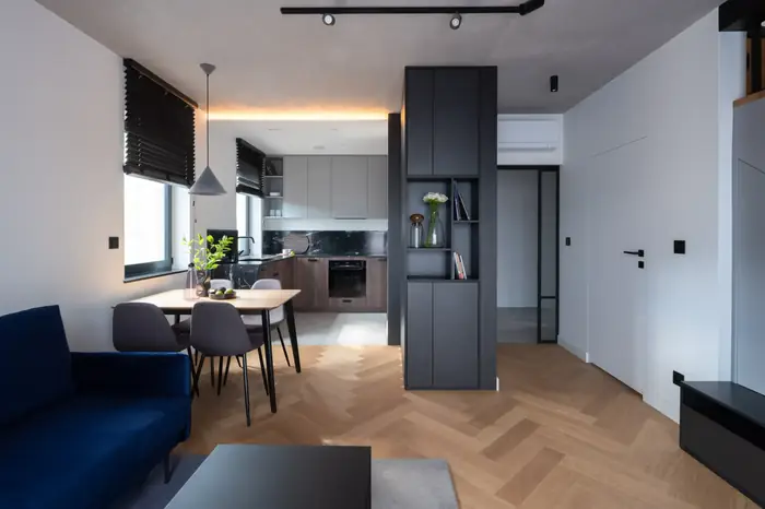 Open-plan kitchen and dining room with herringbone oak flooring and a dark joinery wall.